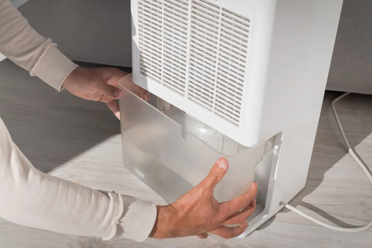 Man changing water container in air dryer, dehumidifier