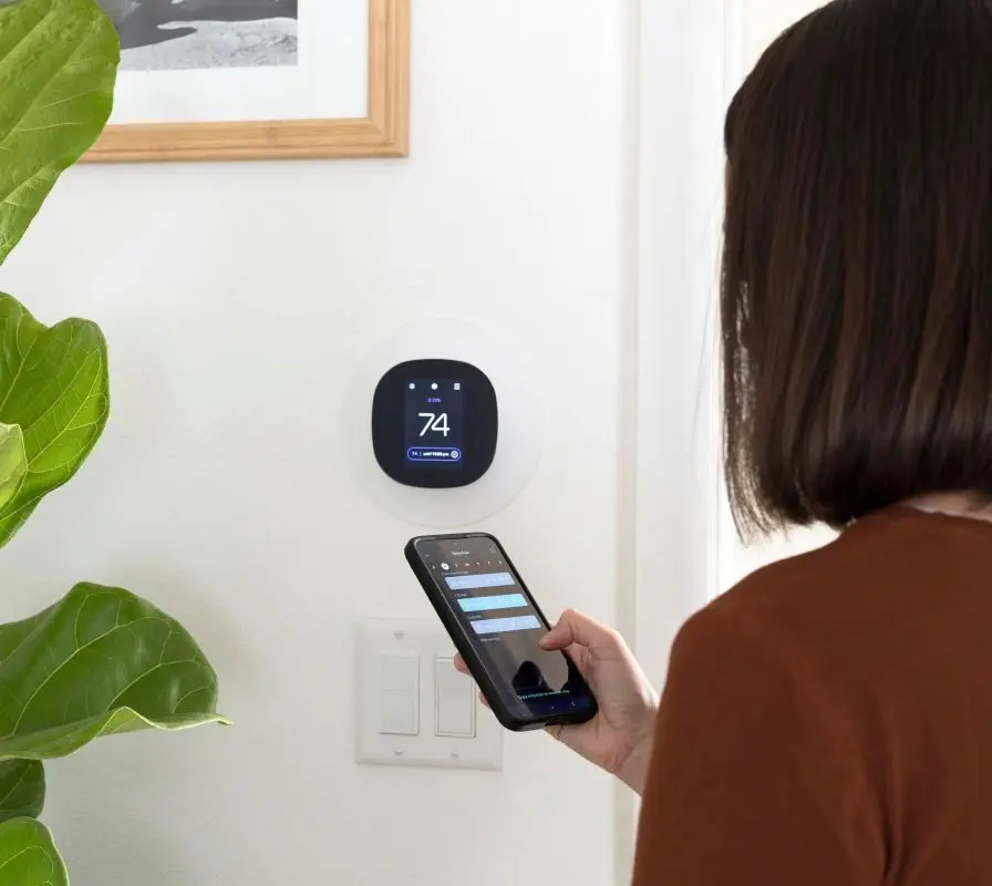 Woman programming a smart thermostat