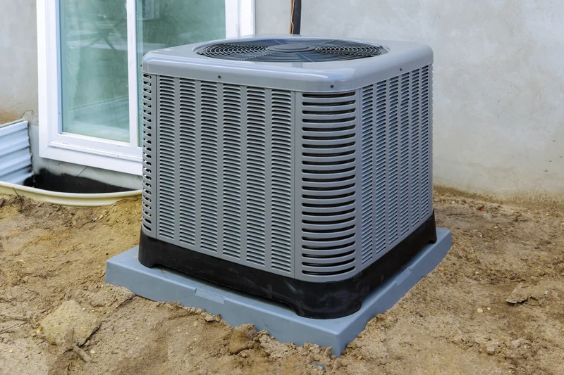 Outdoor air conditioning unit on a concrete slab next to a building.