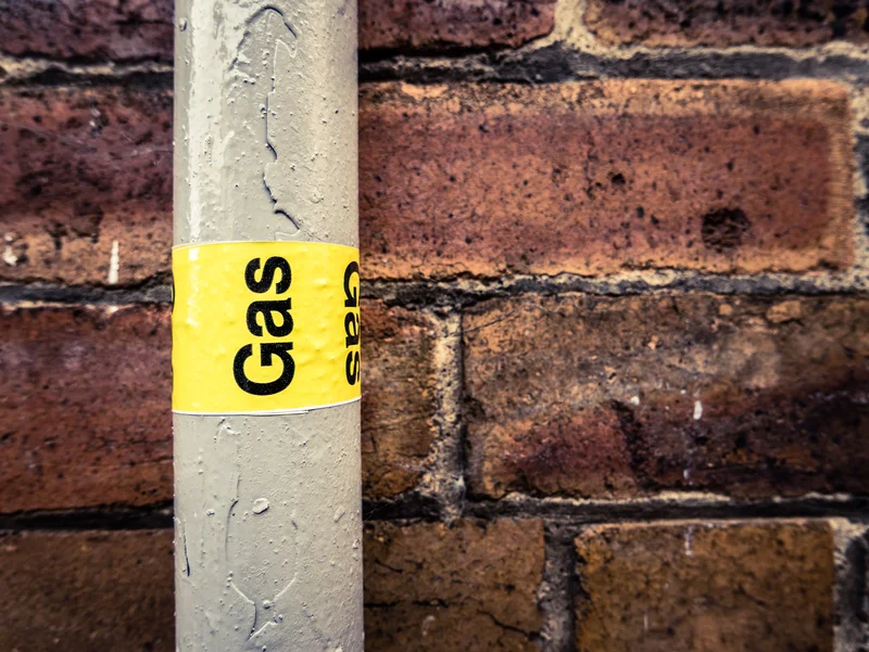 gas labeled pipe on brick wall
