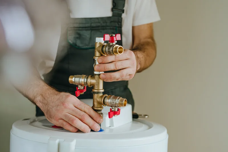 closeup hands connecting brass valves on water heater tank