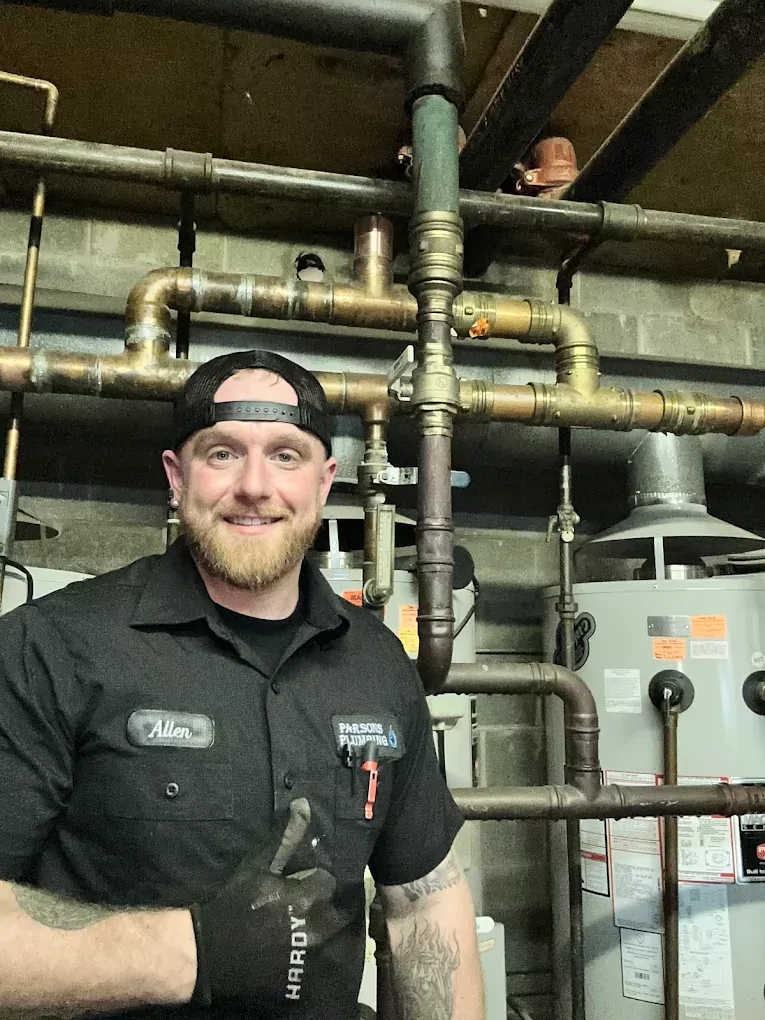 plumber smiling next to a water heater