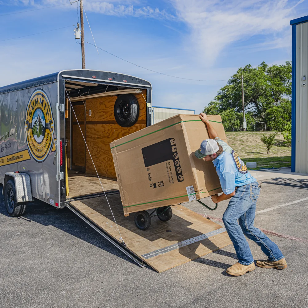 Summit Air Conditioning & Heating team member loading an HVAC unit into a vehicle