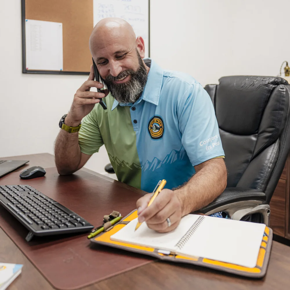 Summit AC crew member in an office talking on the phone and taking notes