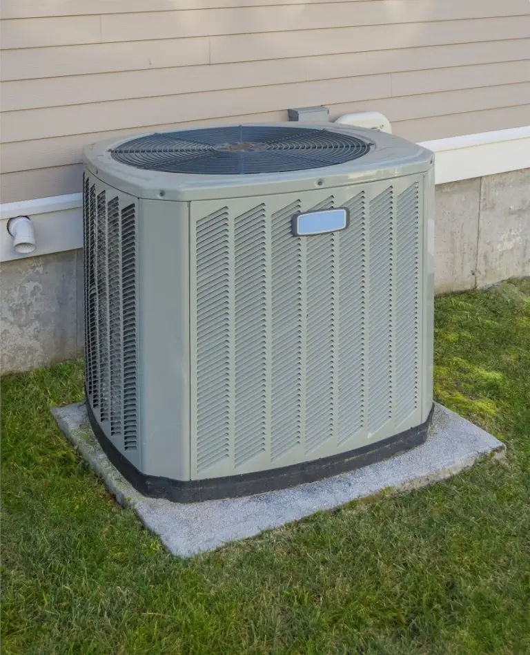 Outdoor air conditioning unit on a concrete pad near the side of a house.