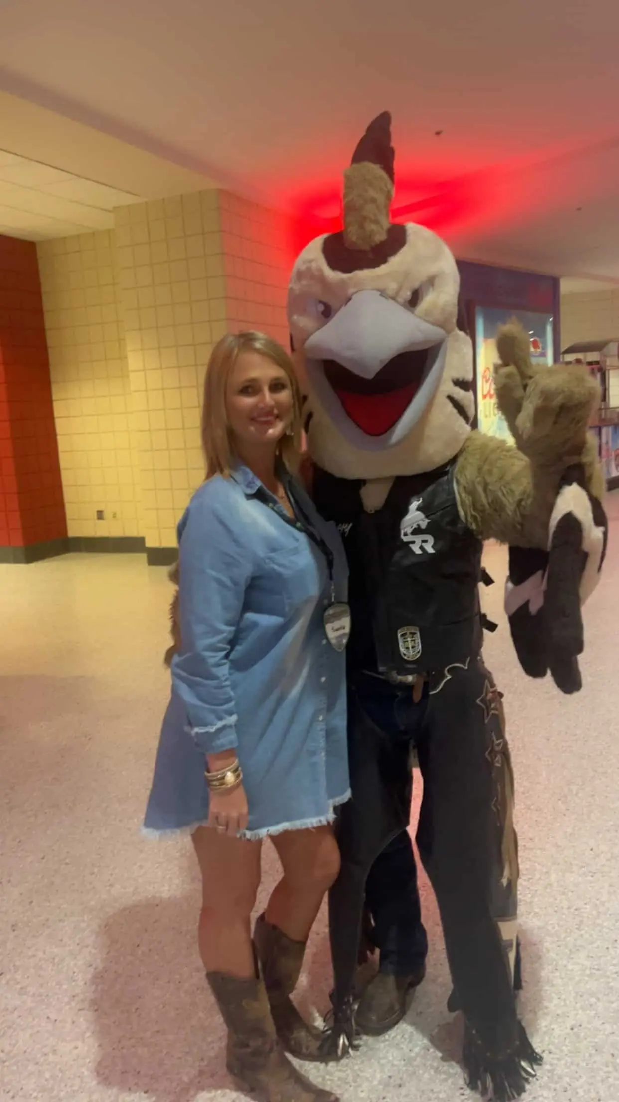 Woman posing with a large, friendly cartoon bird mascot.
