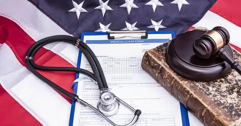 Veteran VA disability claim form with gavel and stethoscope VA disability claim form, gavel, and stethoscope on American flag.