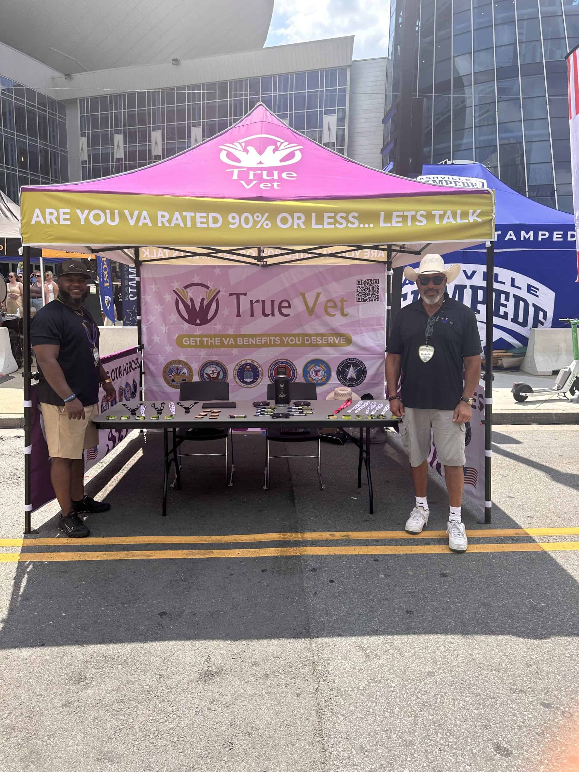 Vet booth promoting VA ratings with a pink canopy and informational displays.