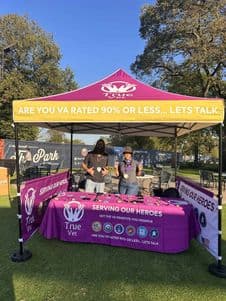 Two people standing behind a booth with banners promoting vaccination and health awareness.
