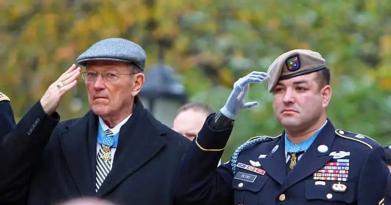 Veteran and soldier saluting at ceremony Veteran and soldier saluting during a military ceremony outdoors.