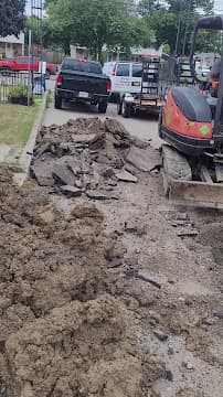Mini excavator digging trench for underground sewer line repair
