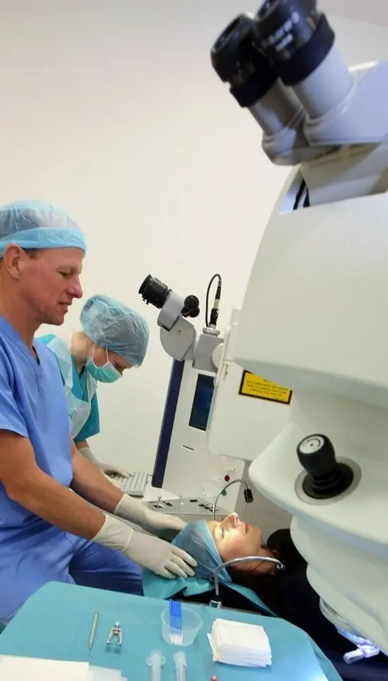 Ophthalmologist Dr Mark Wevill assuring a patient who is lying down for a laser treatment