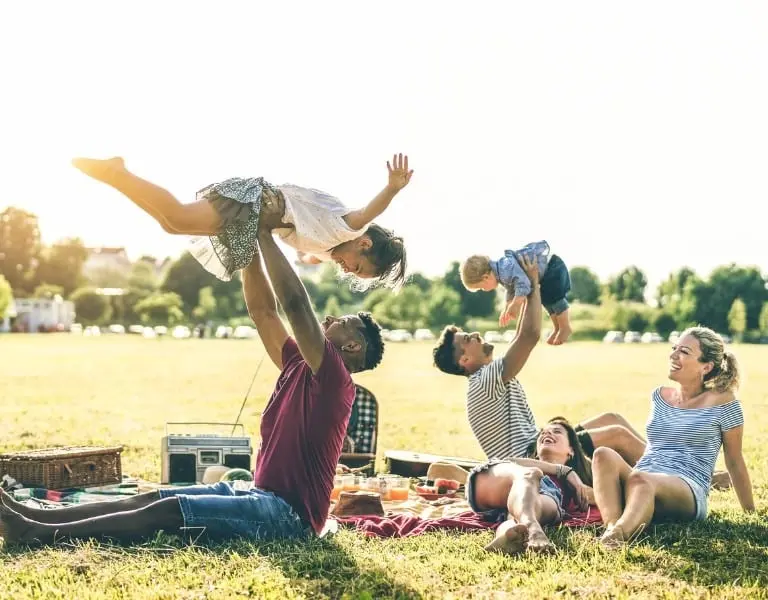 Happy families enjoying a sunny picnic, symbolizing the financial security and living benefits offered by Doyle Assurance Group’s life insurance plans.