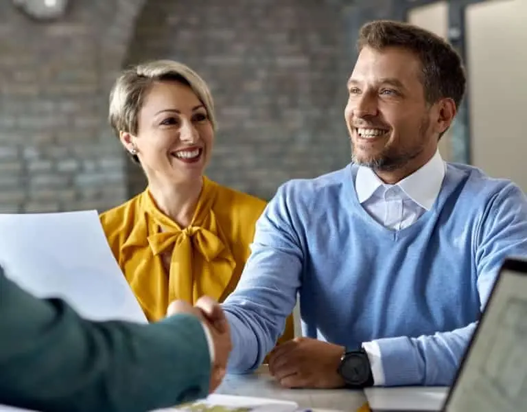 Smiling couple meeting with an insurance advisor to secure mortgage protection insurance and financial security.