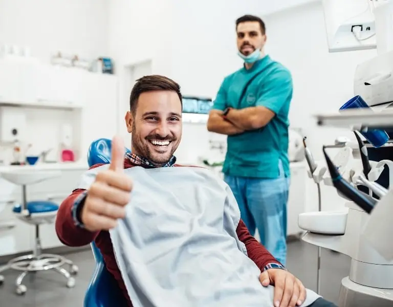Smiling man in a dental chair giving a thumbs-up, representing supplemental health insurance coverage for dental care in Plano, Texas.