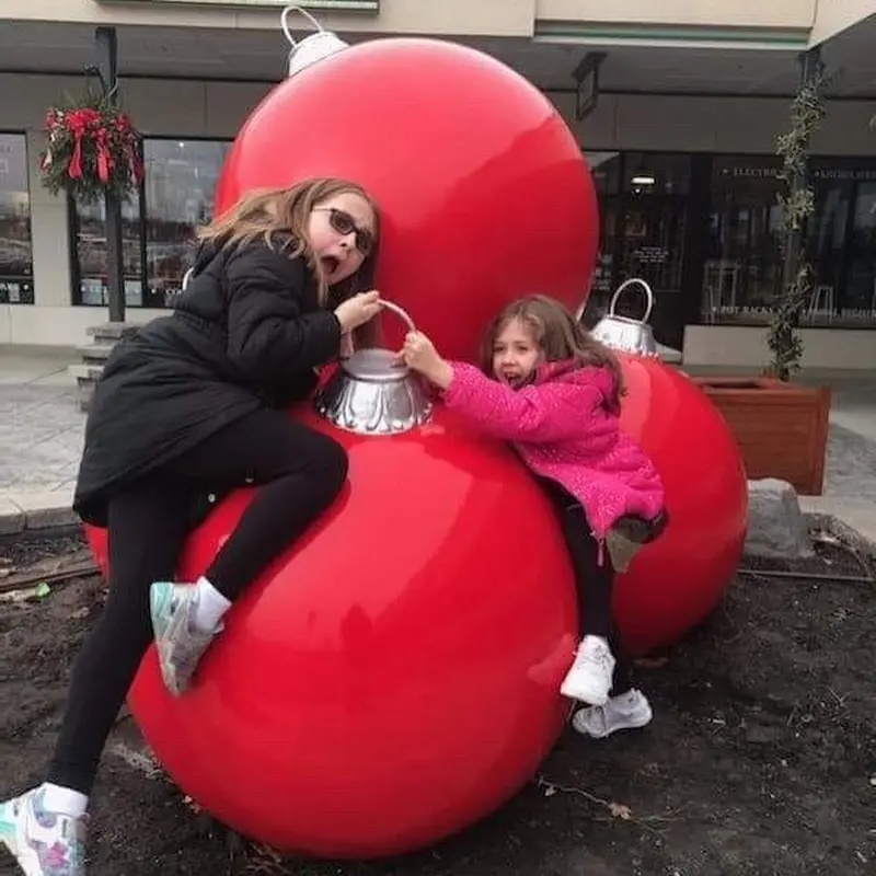 kids playing on giant christmas ornaments