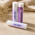 Three Plumera Very Minty handmade lip balm tubes with purple and white labels on a black background