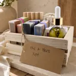 Plumera His and Hers Gift Set in a light wood box with four handmade soaps, dropper oil, balm tins, lip care, soap dish, and fiber accessories