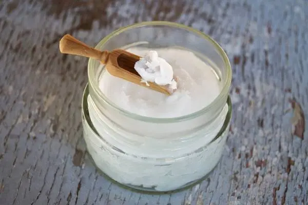 Coconut oil in a glass jar and spoon for a handmade soap ingredient guide
