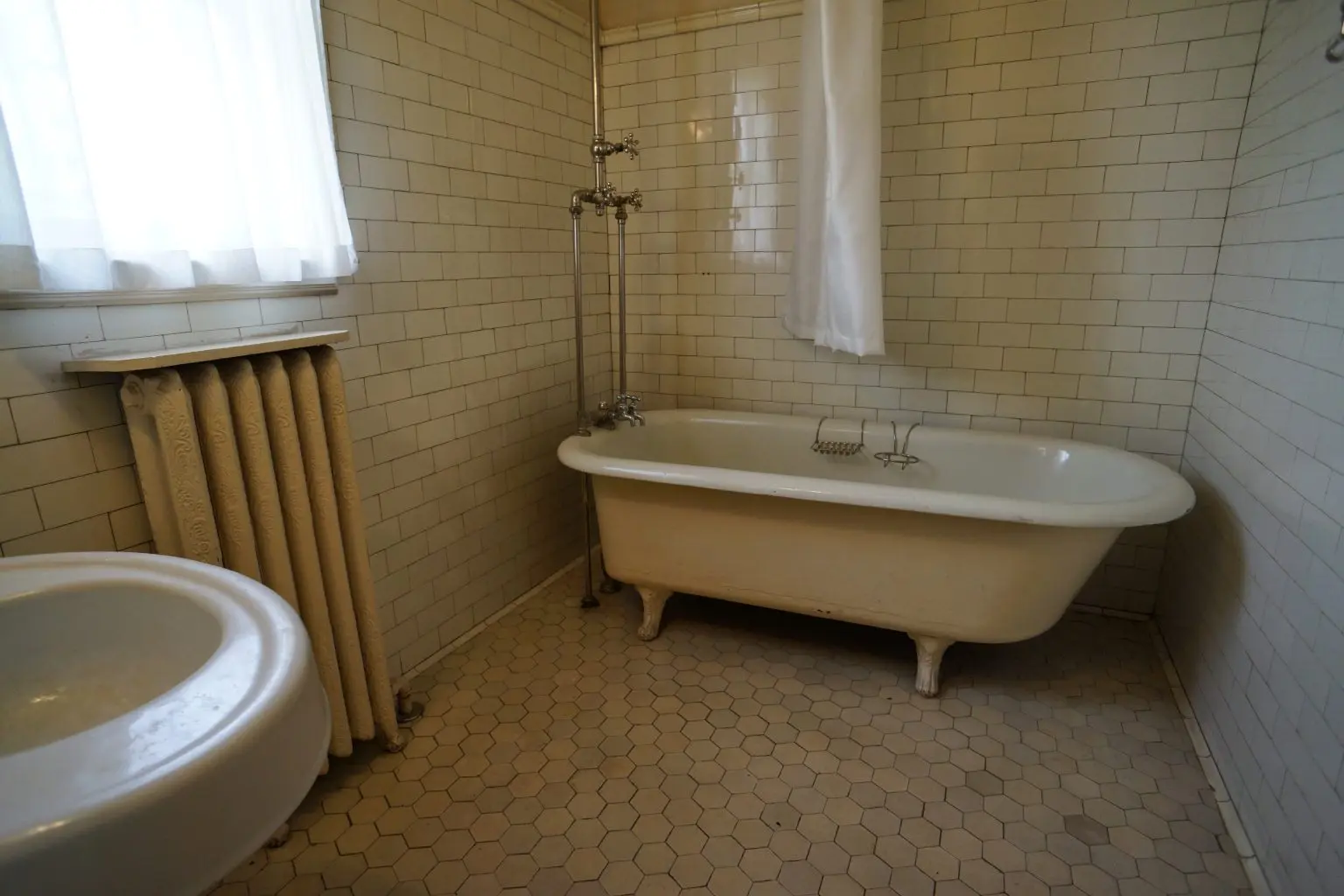 Vintage bathtub and open tiled floor in a sunlit bathroom