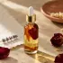 Nourishing botanical face oil in a clear glass dropper bottle in a warm floral editorial setting