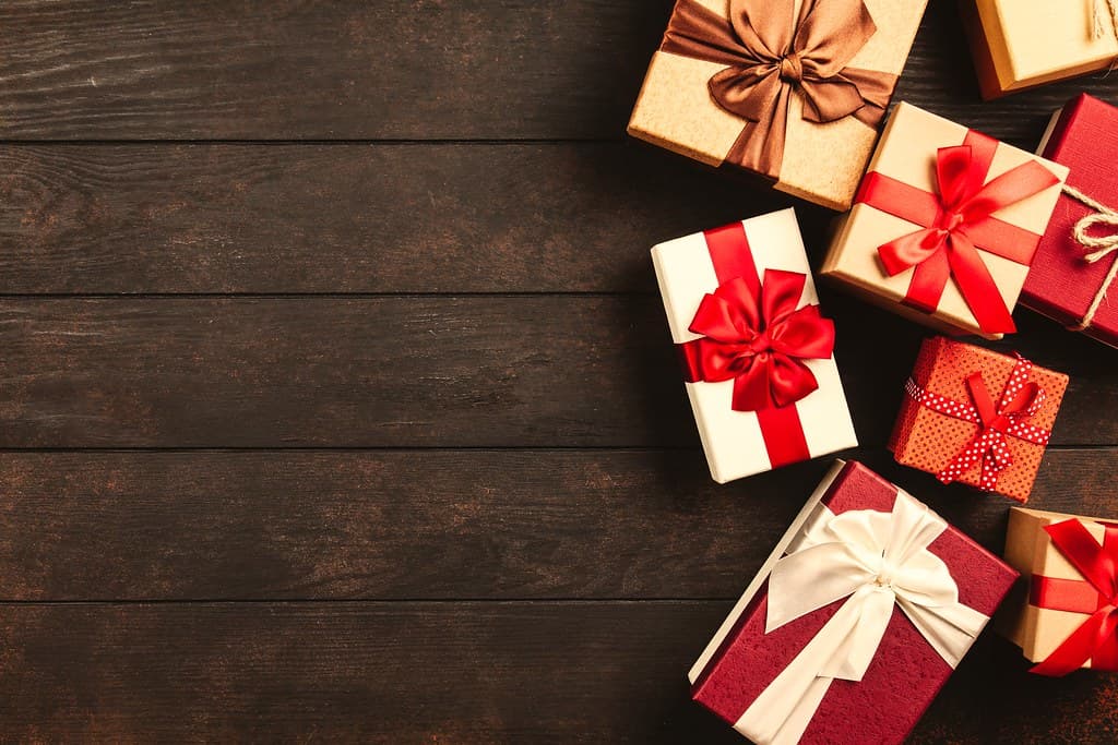 Wrapped holiday gifts with red ribbons on a dark wood table