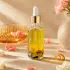 Golden botanical oil in a clear glass dropper bottle with yellow flowers and dark botanicals