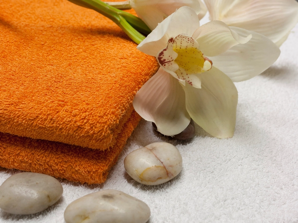 White orchid on soft towels with smooth stones in a clean spa-style setting