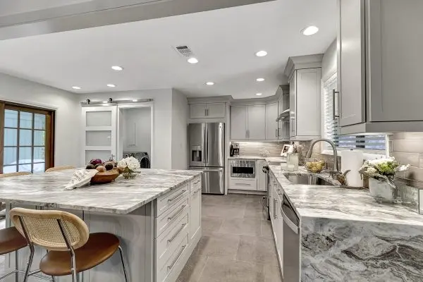 A newly remodeled kitchen with marble countertops and white cabinets