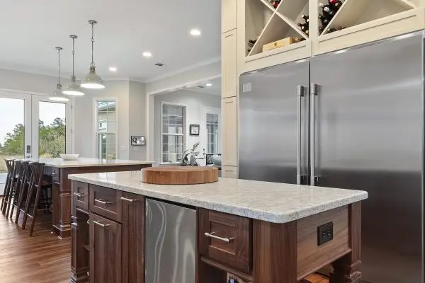 Custom kitchen remodel with small walnut island and over refrigerator wine rack