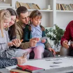 Life Insurance Insights for Oldsmar Residents 2 Family members of various ages engaged in a card game around a coffee table in a cozy living room.