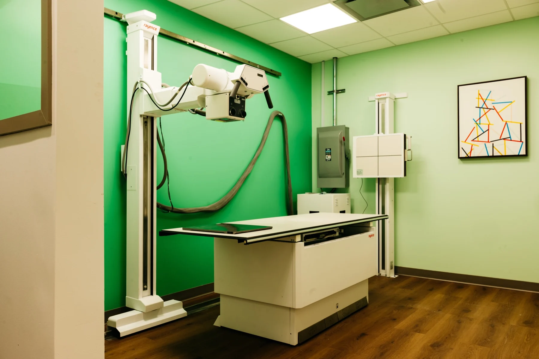 The digital X-ray suite at a Care+ Pediatrics Urgent Care clinic, with the X-ray table and imaging arm