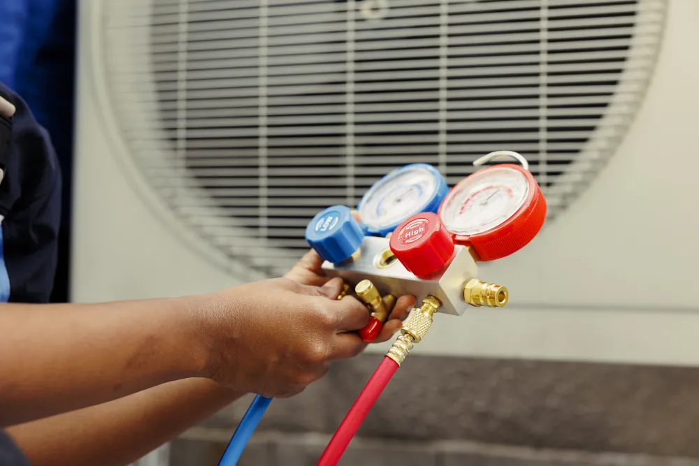 HVAC technician checking for refrigerant leaks using a manifold gauge.