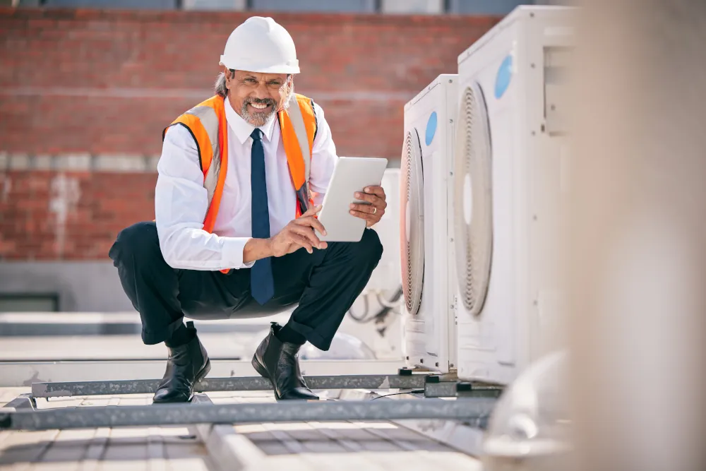 HVAC sizing for commercial spaces - HVAC worker crouching next to commercial HVAC units.