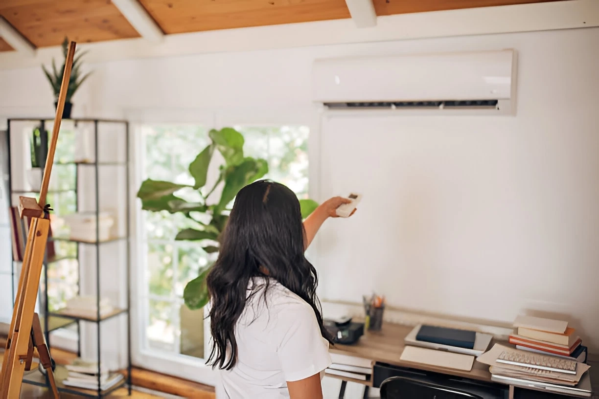 Woman pointing remote control at a mini split