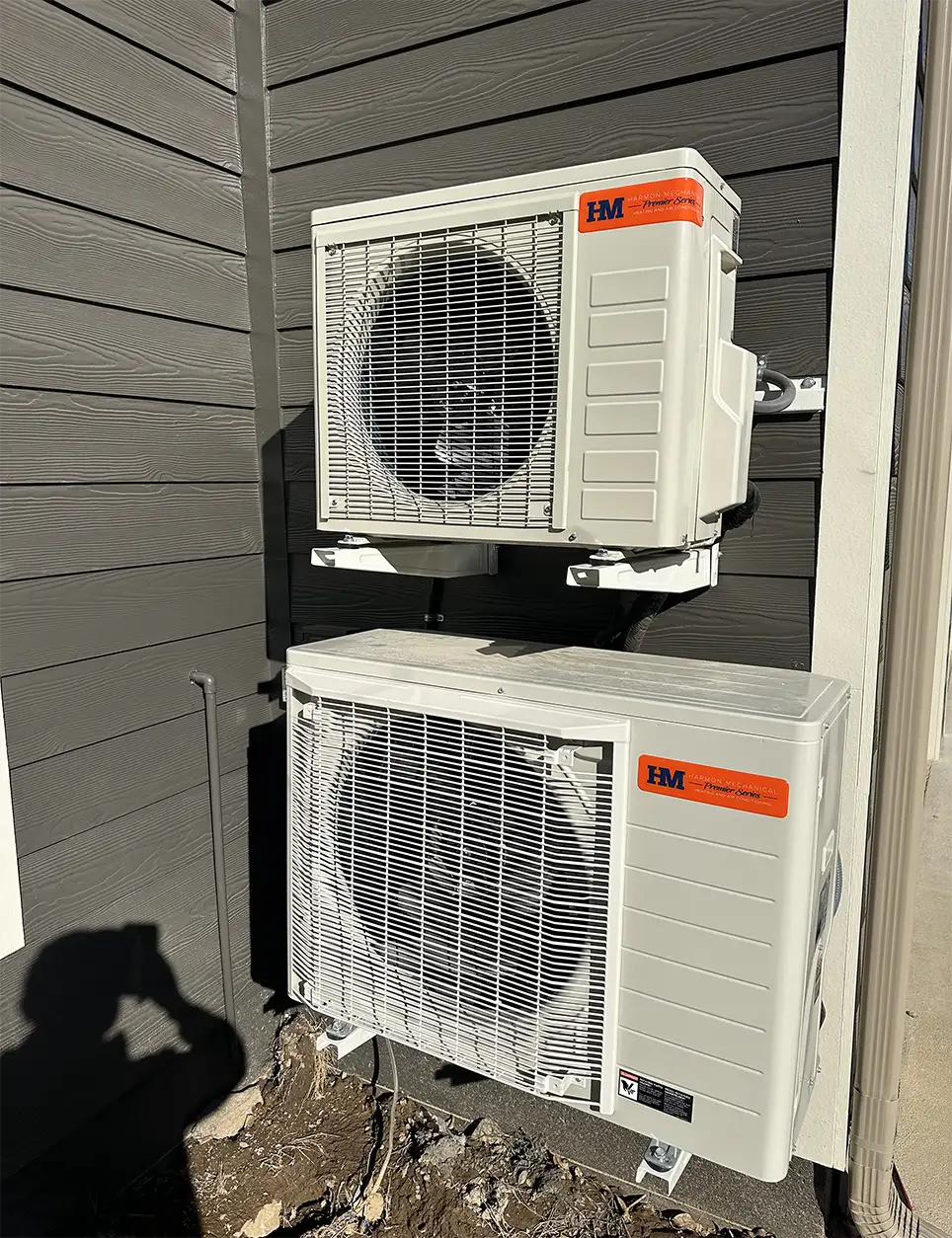 Two outdoor HVAC units with Harmon Mechanical brand sticker