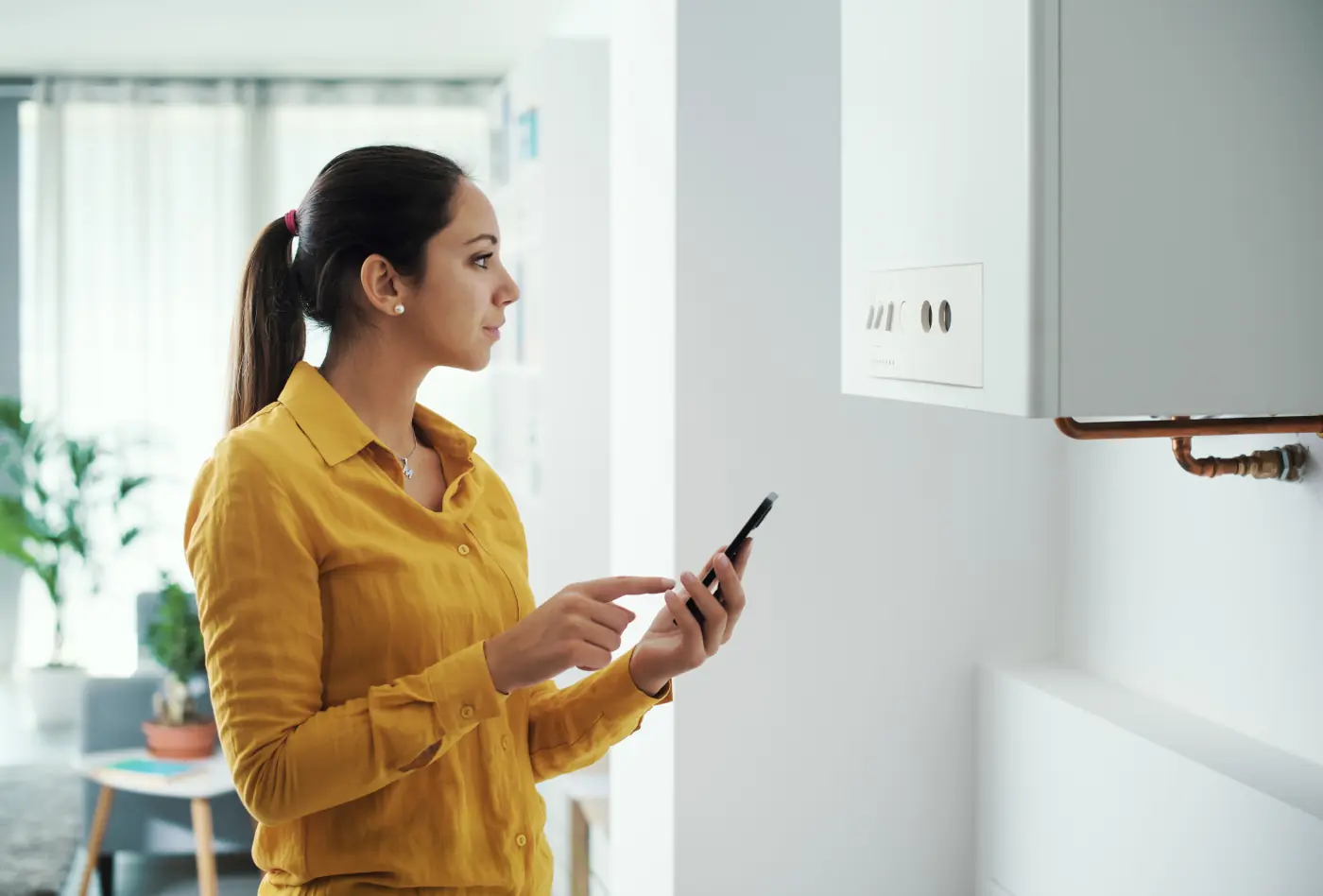 Woman with her phone in front of a boiler
