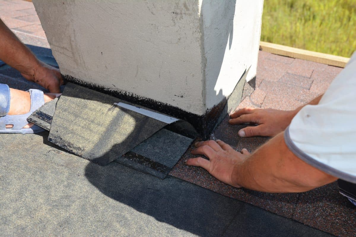 roof flashing A close-up on a roofing construction, installation of asphalt shingles on roof sheathing around a house chimney using waterproofing corner flashing. Roofing construction.