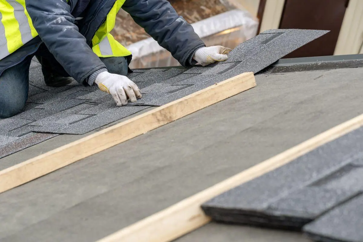 guy using white gloves installing grey shingles