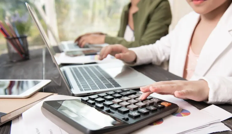 Business professionals analyzing financial data and using calculator for strategic planning and internal controls.