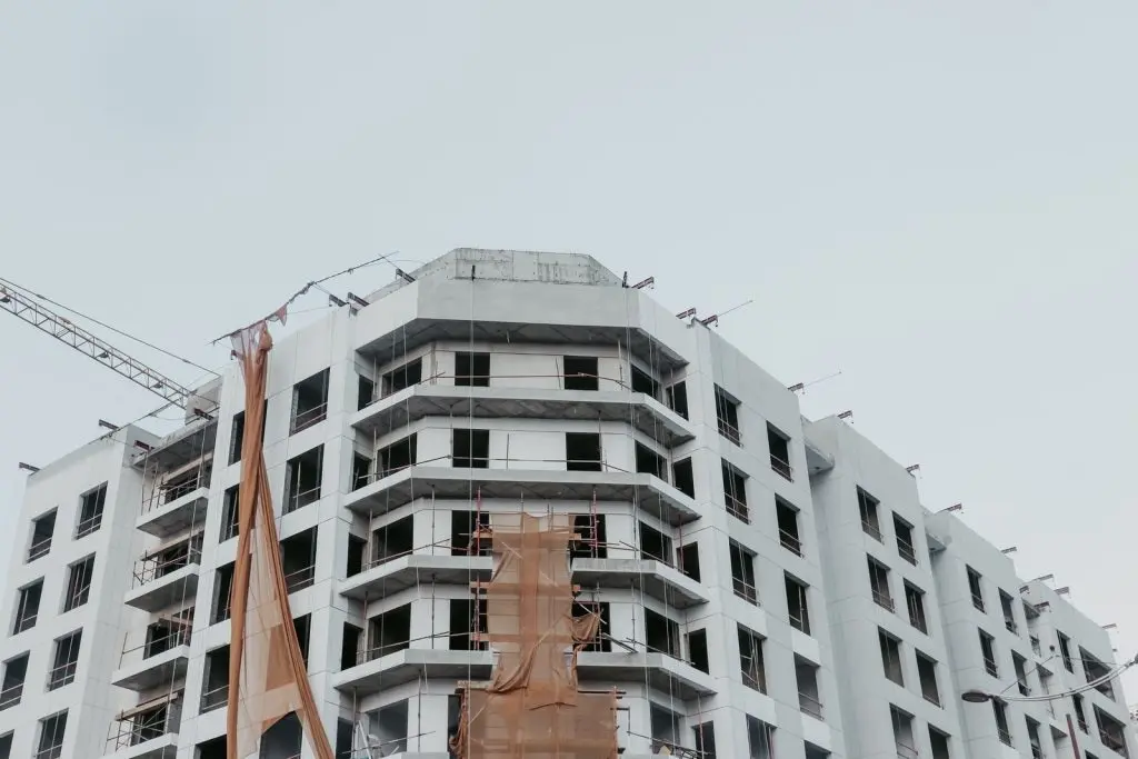 Mid-rise building near the end of construction, with scaffolding and a crane