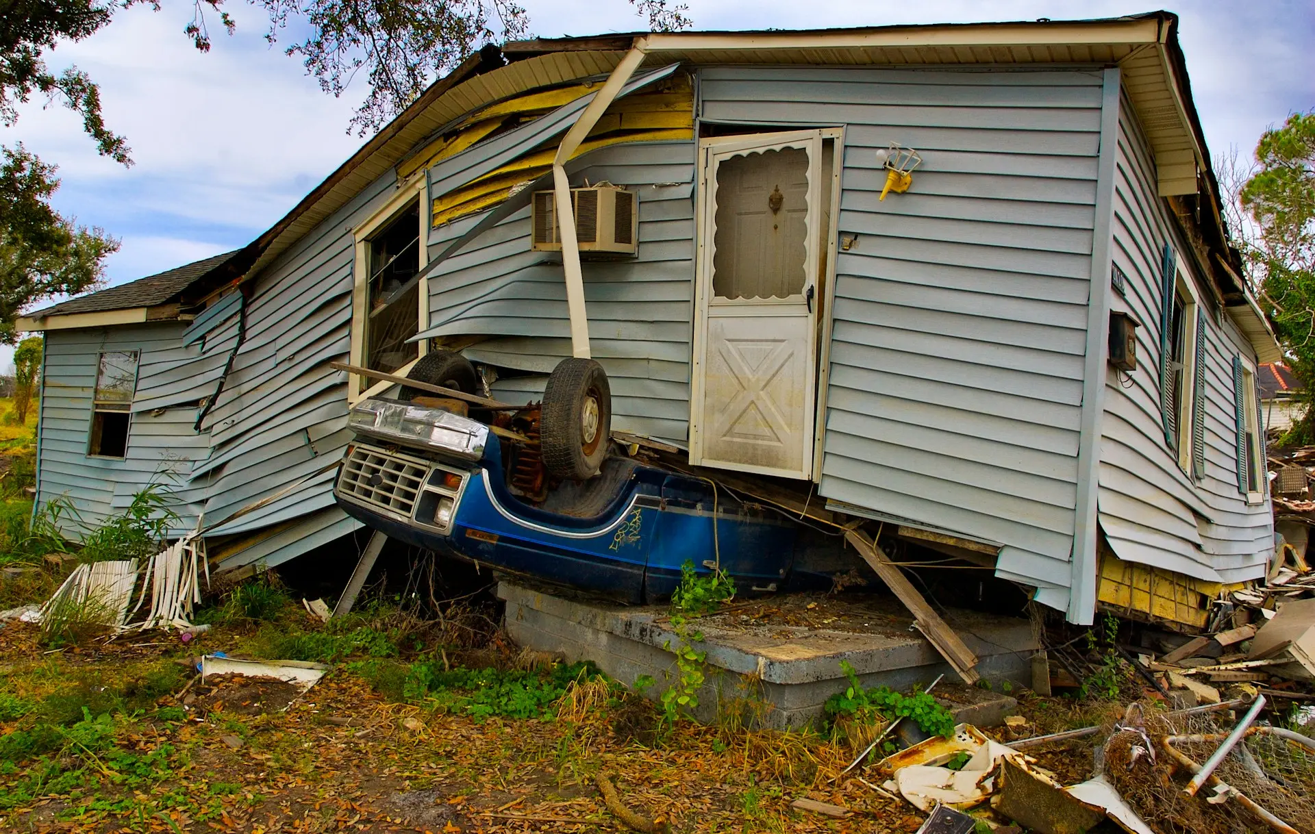 Overturned truck crushed under home highlighting disaster debris destruction