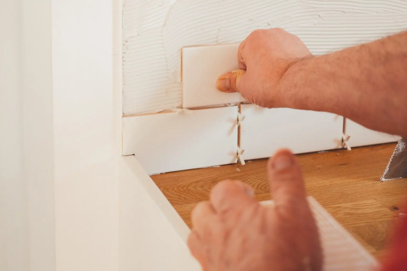 Installing kitchen backsplash tiles during a home renovation project