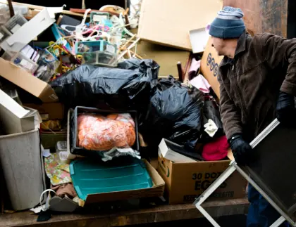 Man loading household trash and boxes into a dumpster rental