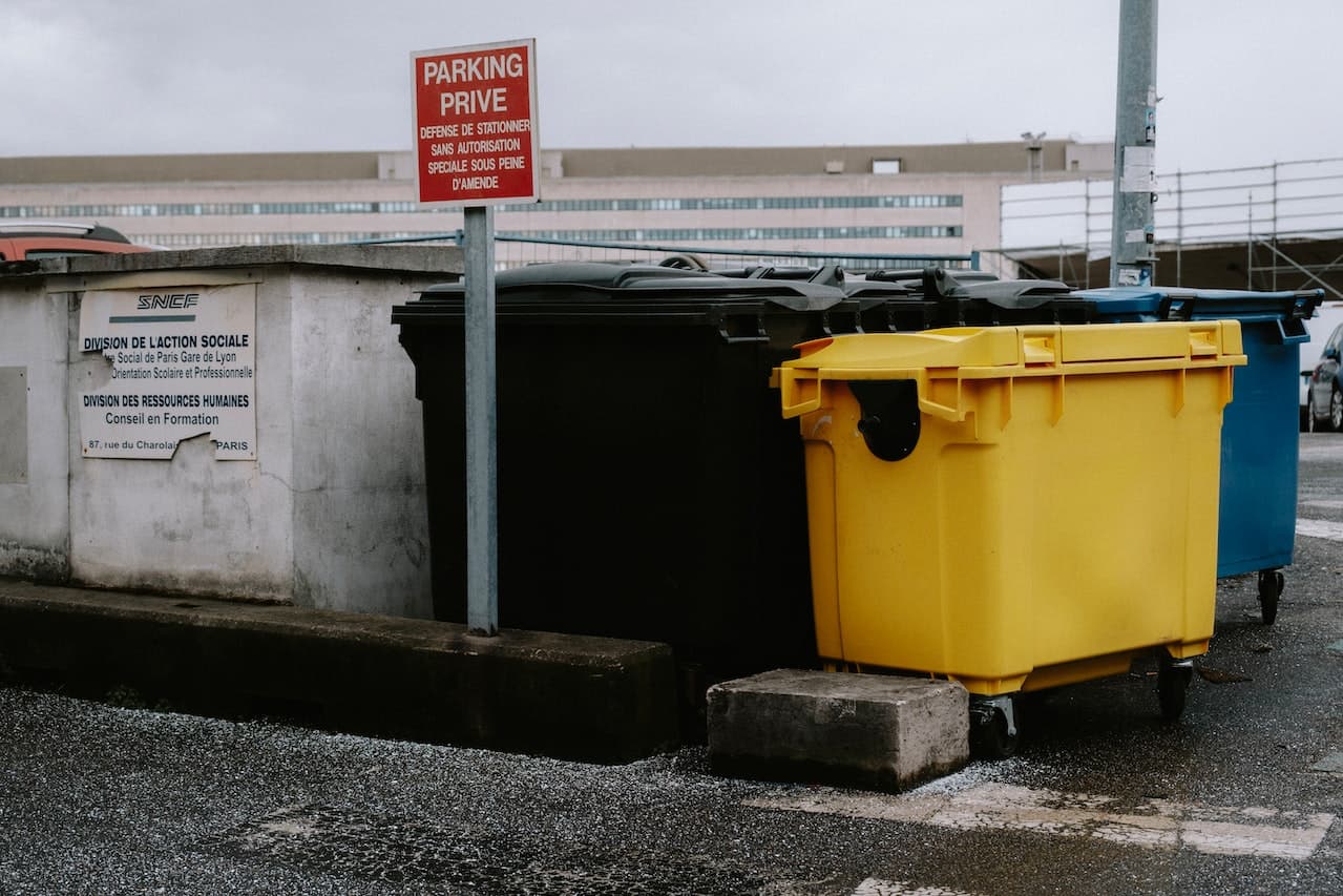 Color-coded industrial dumpsters parked near private parking sign