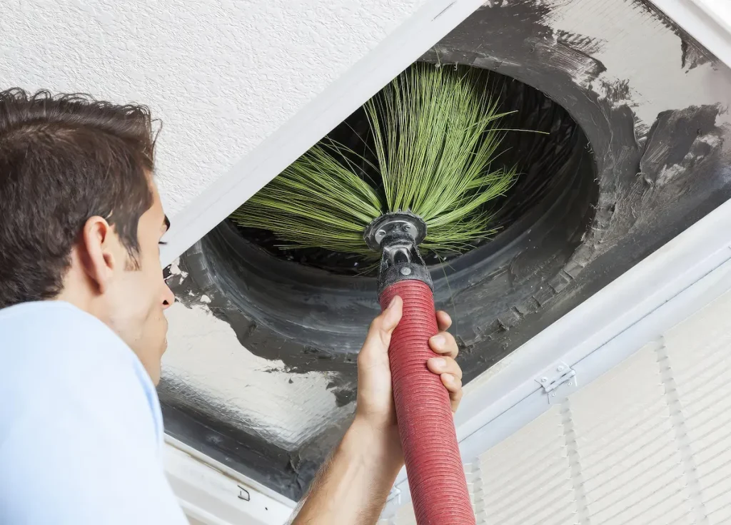 hvac worker cleaning air duct