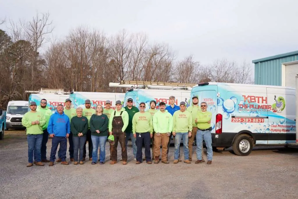 The team of Keith The Plumber posing for a group photo in front of their branded service vans