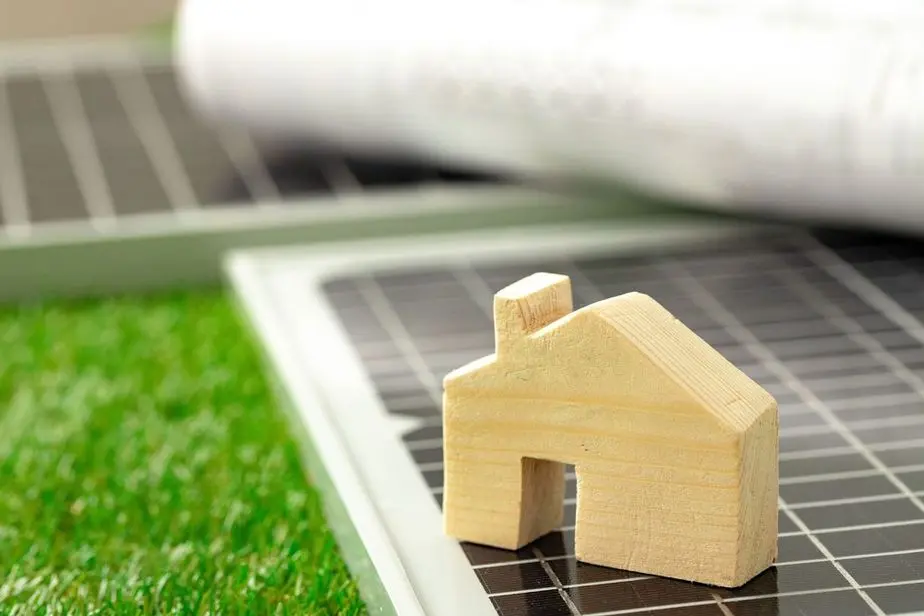 Wooden house miniature and solar panel close up, green energy concept