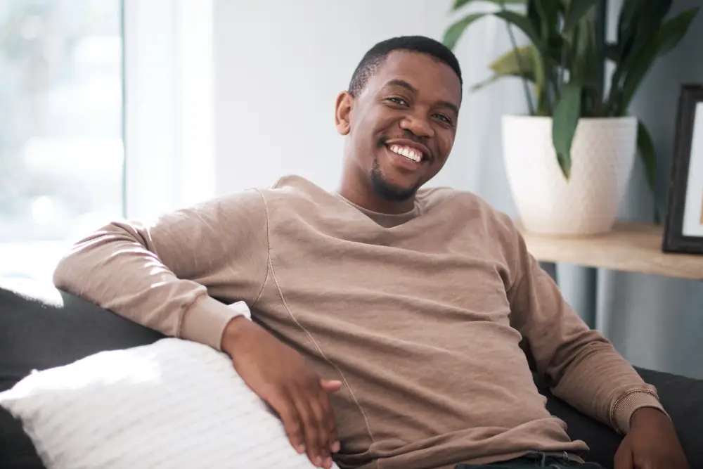 Upgrade Your Comfort, Finances, and Environmental Impact: Unleash the Power of Heat Pumps for Savings and Sustainability! - Man sitting on a sofa while smiling at the camera