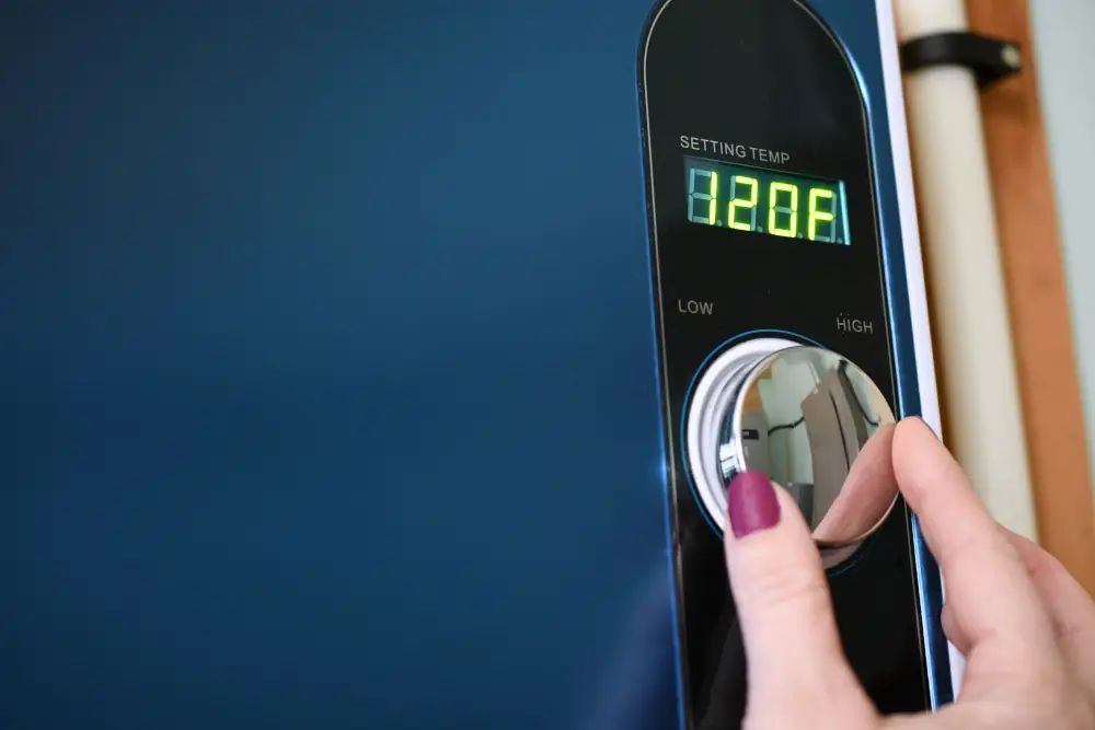 How Tankless Water Heaters Can Save You Money - hand adjusting temperature on a tankless water heater